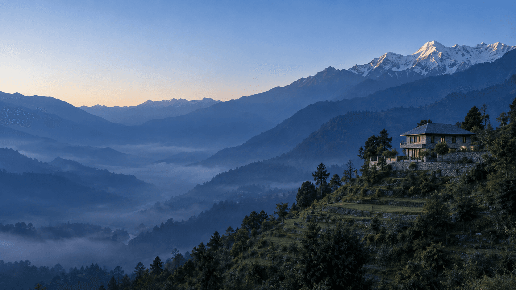 Stone hill house on a terraced ridge above a misty Garhwal valley, snow peaks catching first light in Uttarakhand
